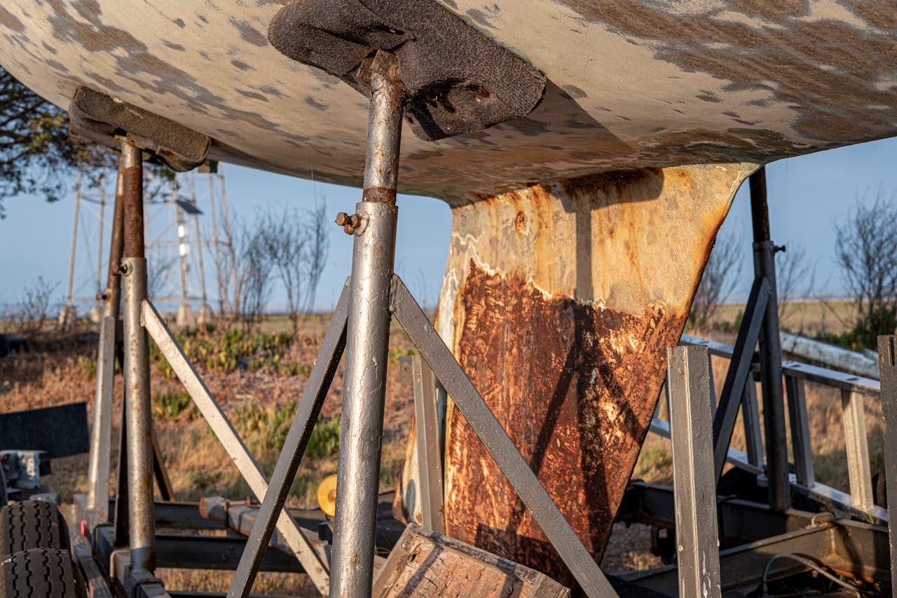 Close-up view of a rusty boat keel on a metal support structure outdoors.